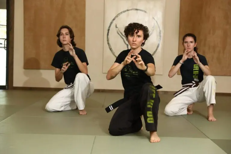 Brazilian Jiu Jitsu students practicing kneeling guard stance drills on dojo mats during training session.