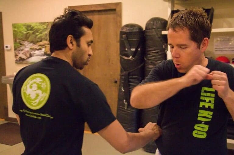 Two men perform a close-quarters grappling drill in brazilian jiu jitsu classes at a martial arts academy.