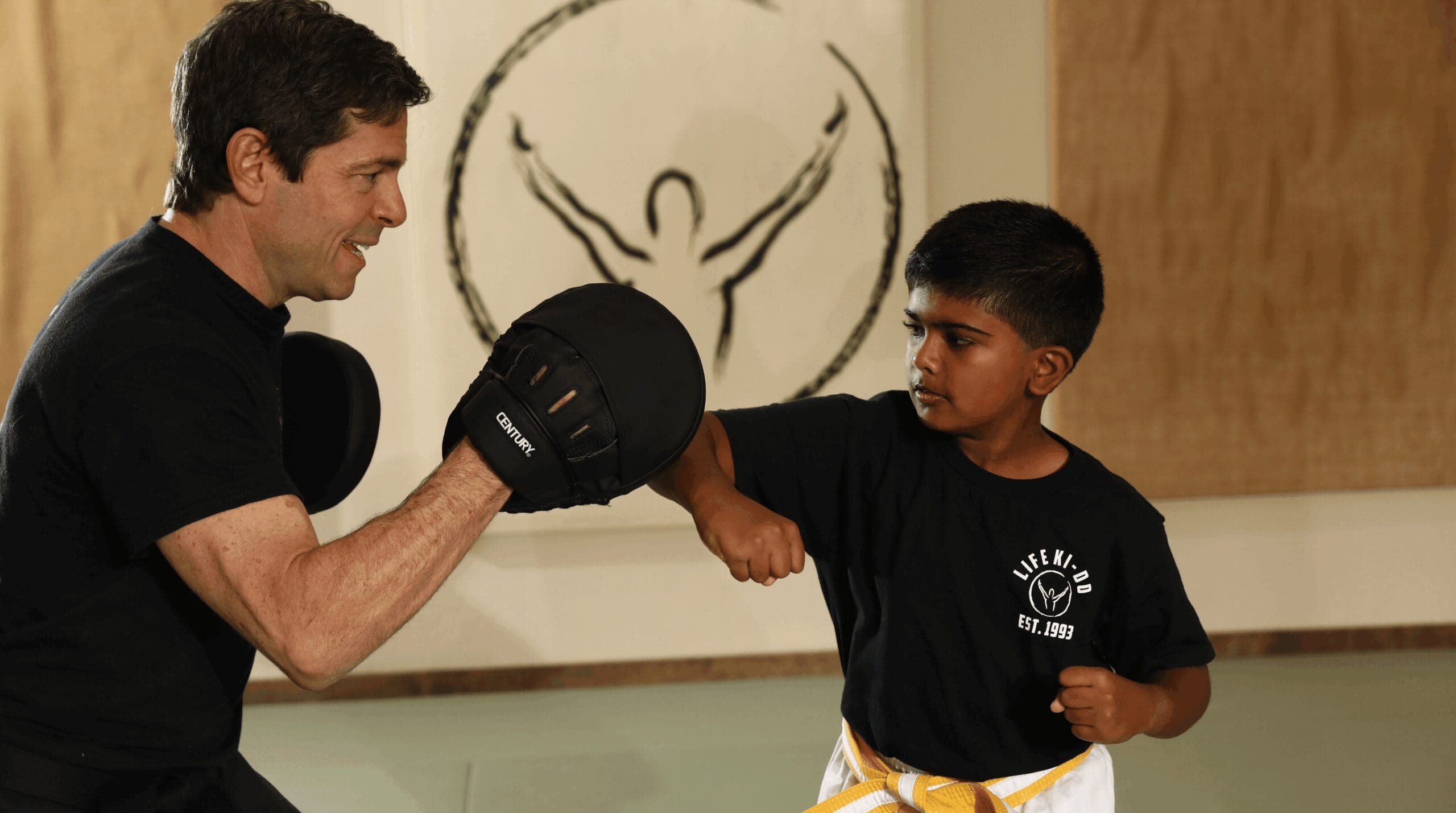 Young student learning proper punching technique with a martial arts instructor to build confidence and coordination.