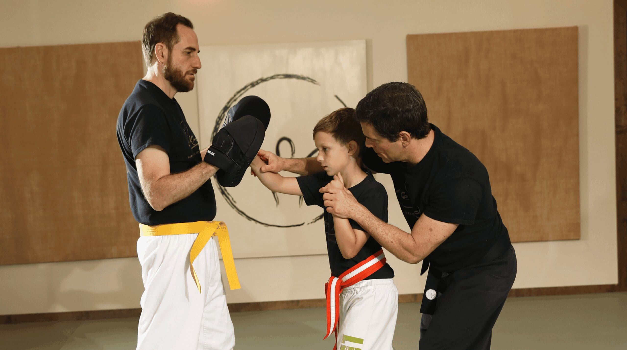 Martial arts instructor providing personalized guidance to help a child learn correct technique with confidence and patience.